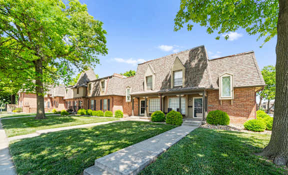 A large house with a brick exterior and a green lawn in front.