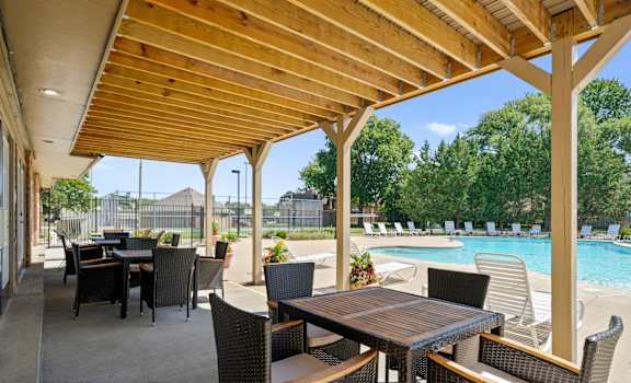 A patio with a table and chairs overlooking a pool.