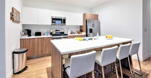 a kitchen with a large island and white chairs