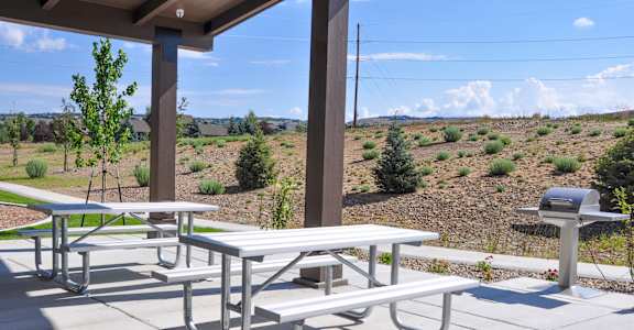 Picnic tables are set up on a patio with a view of a field.