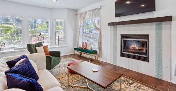 A living room with a fireplace and a television mounted above it.