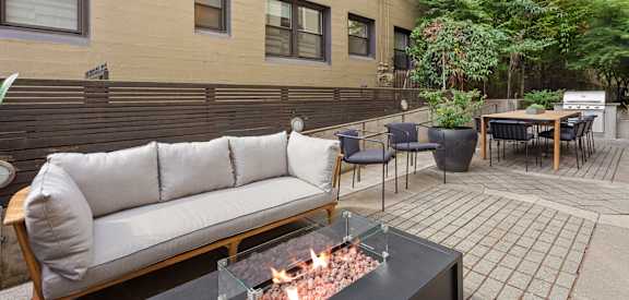 a patio with a couch and tables and a fire pit