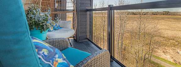 a balcony with two chairs and a window overlooking a field