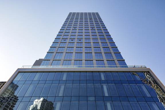 A tall building with blue glass windows stands against a clear sky.