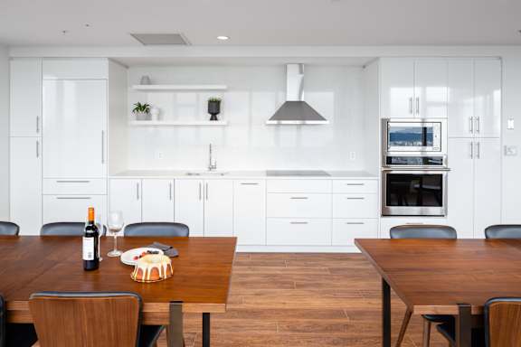 A modern kitchen with a wooden table set for two.