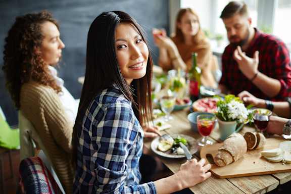 A group of people are sitting around a table enjoying a meal together.