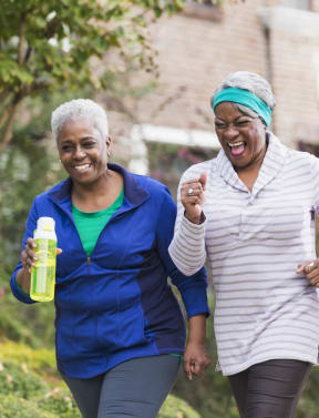 three women walking together and laughing while holding water bottles
