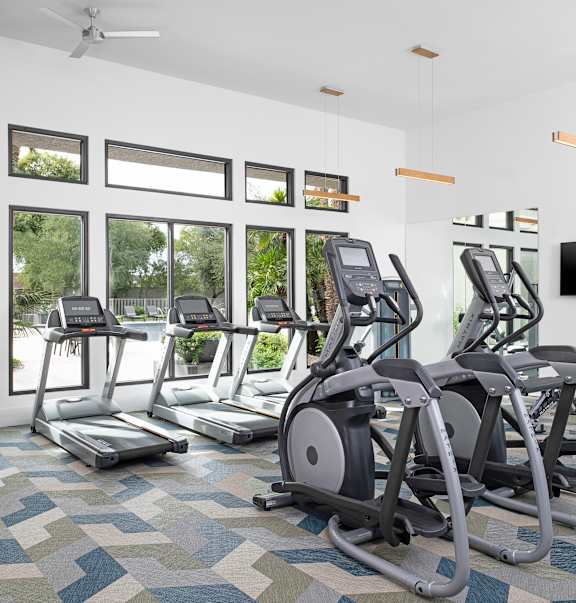 A gym with treadmills, exercise bikes, and a television.