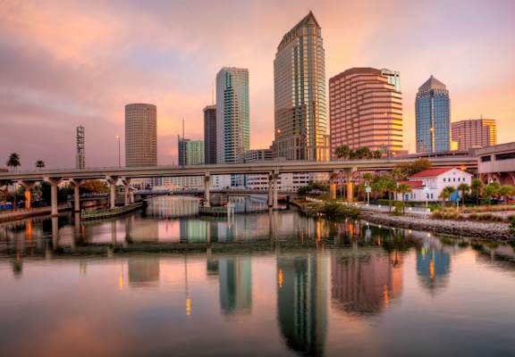 A city skyline with tall buildings reflected in the water.