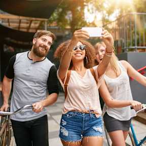 Three friends are riding bicycles and taking a selfie.