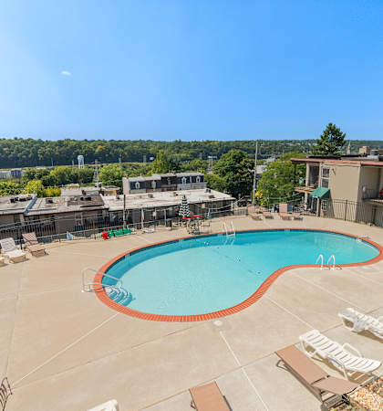 an aerial view of a swimming pool at a hotel with chairs and tables and trees