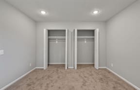 an empty bedroom with two closets and a carpeted floor