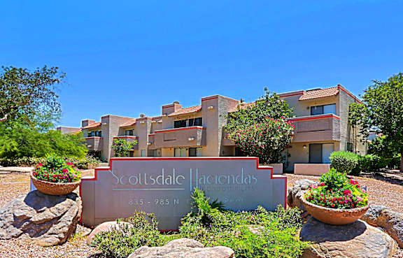 The Scottsdale Hacienda sign is in front of a building with a clear blue sky in the background.