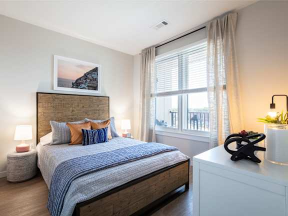 A bedroom with a bed, nightstand, and a window with curtains.