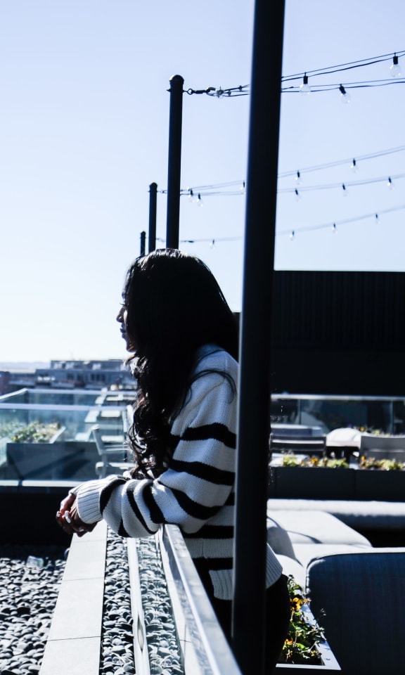 a woman sitting on a balcony overlooking a city