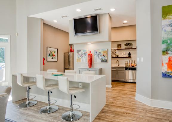 A modern kitchen with white bar stools and a white counter.