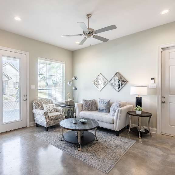 A modern kitchen with a stainless steel refrigerator and a dining area with a white sofa and a coffee table.