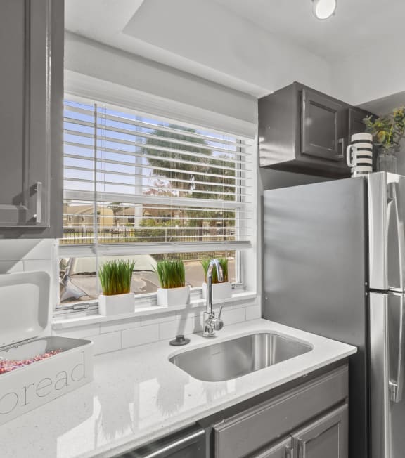 a kitchen with stainless steel refrigerator and sink and a window