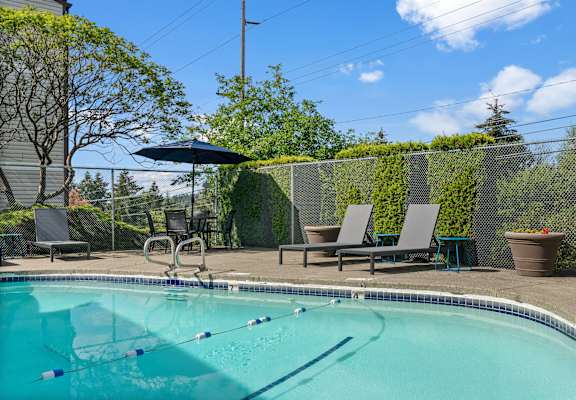 A swimming pool with a diving board and lounge chairs.
