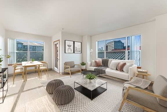 A living room with a white couch, a coffee table, and a dining table.