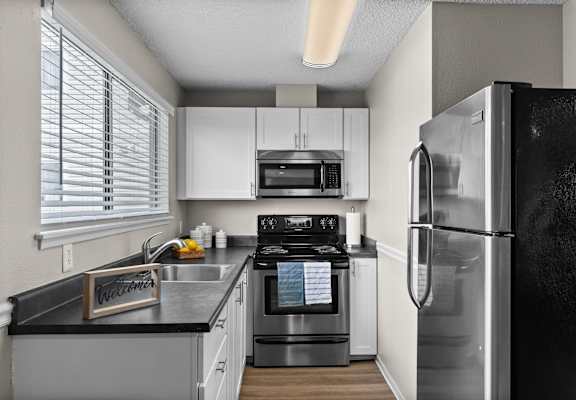 A kitchen with a black fridge and white cabinets.