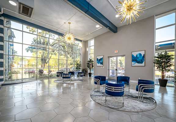 a lobby with blue chairs and large windows and a chandelier