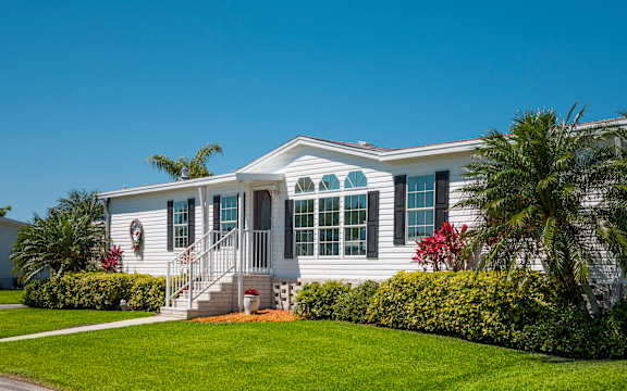 a white house with green shutters and palm trees