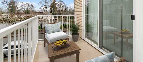 A balcony with a table and chairs overlooking a wooded area.