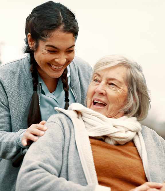 An elderly woman is being comforted by a younger woman in a park.