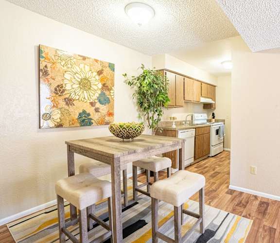 A dining area with a table and chairs and a painting on the wall.