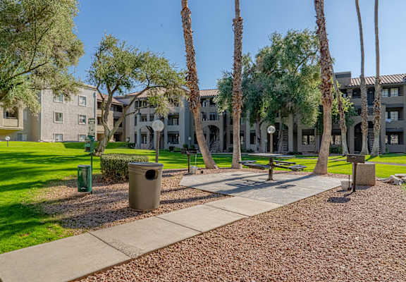 a park with benches and trees in front of an apartment building