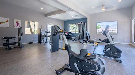A gym with a variety of equipment including a treadmill, a stationary bike, and a weight bench.