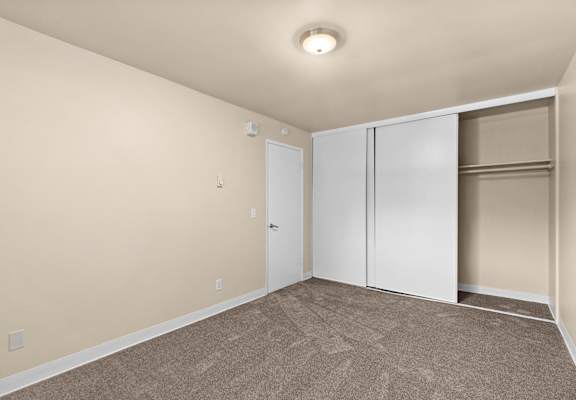 an empty room with carpet and two closet doors