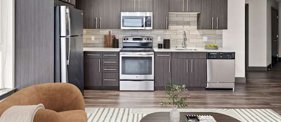 A modern kitchen with a refrigerator, oven, and microwave.