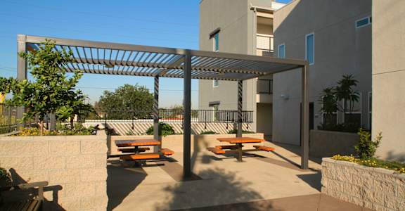 a patio with benches and awning in front of a building