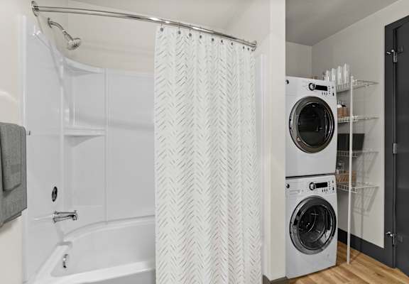 A white bathroom with a shower curtain and a washing machine.