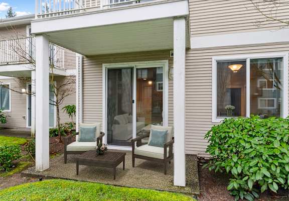 A patio with a table and two chairs is covered by a white awning.