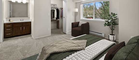 A bedroom with a bed, chair, and closet.