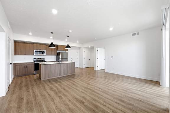 A spacious kitchen with wooden floors and a modern design.