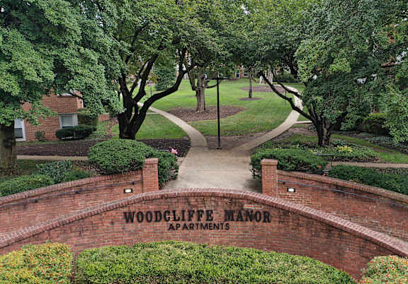 A brick archway with a sign that says Woodcliffe Mansion Apartments.