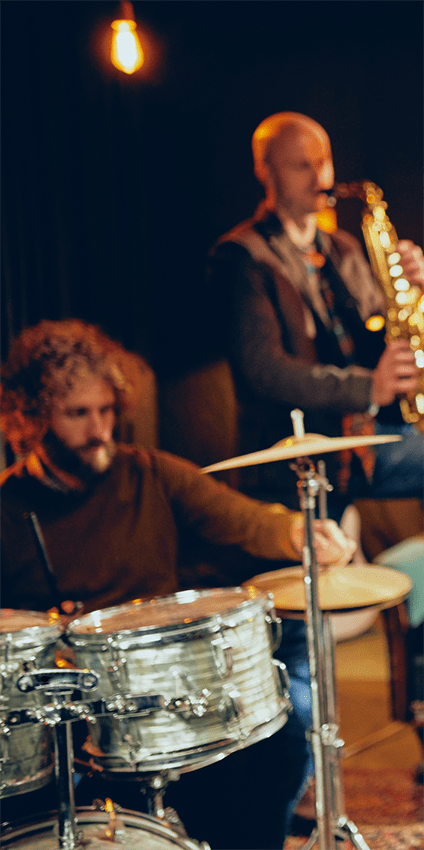 A man playing the saxophone and another man playing the drums.