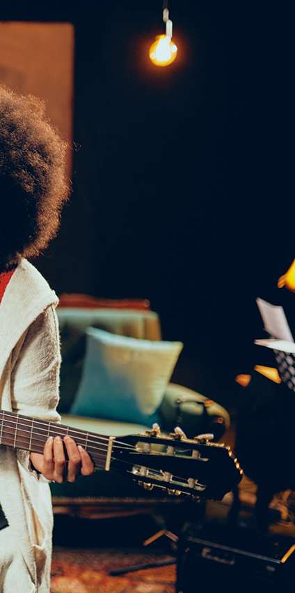 A person with an afro hairstyle is playing a guitar.