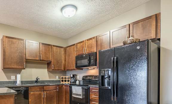 a kitchen with black appliances and warm brown cabinets