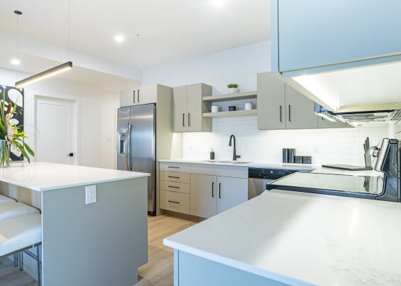 a white kitchen with stainless steel appliances and white counter tops