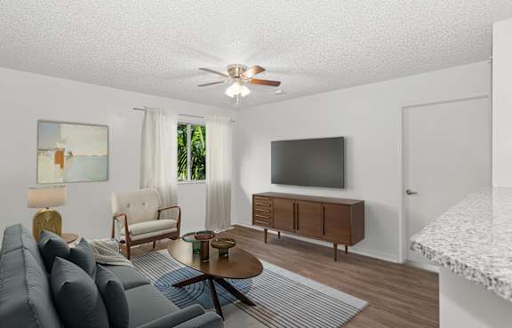 A living room with a grey sofa, a wooden coffee table, a flat screen TV, and a painting on the wall.