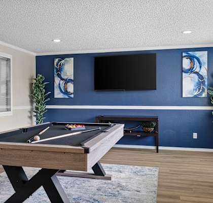A pool table in a room with blue walls and a flat screen TV.