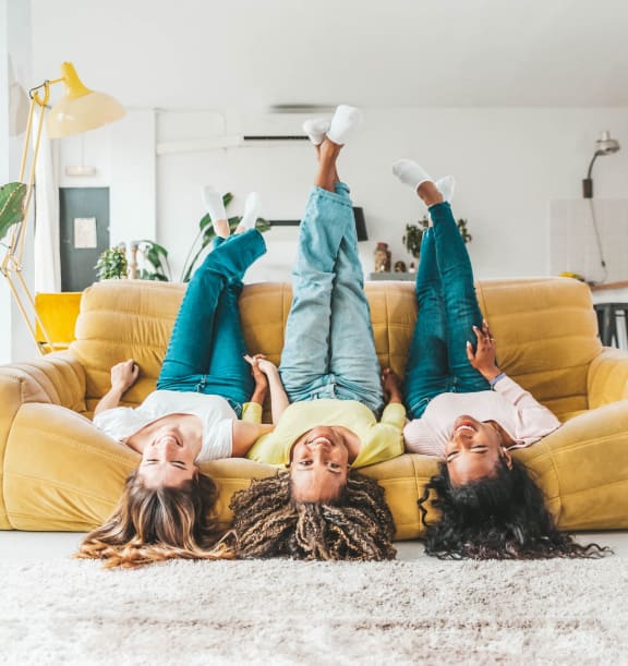 three women laying on a couch with their feet up in the air