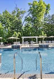 a swimming pool with chairs and umbrellas and trees