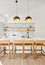 A kitchen with a white counter and wooden chairs.