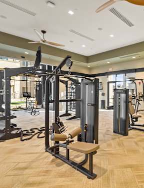 a spacious fitness room with cardio equipment and weights
